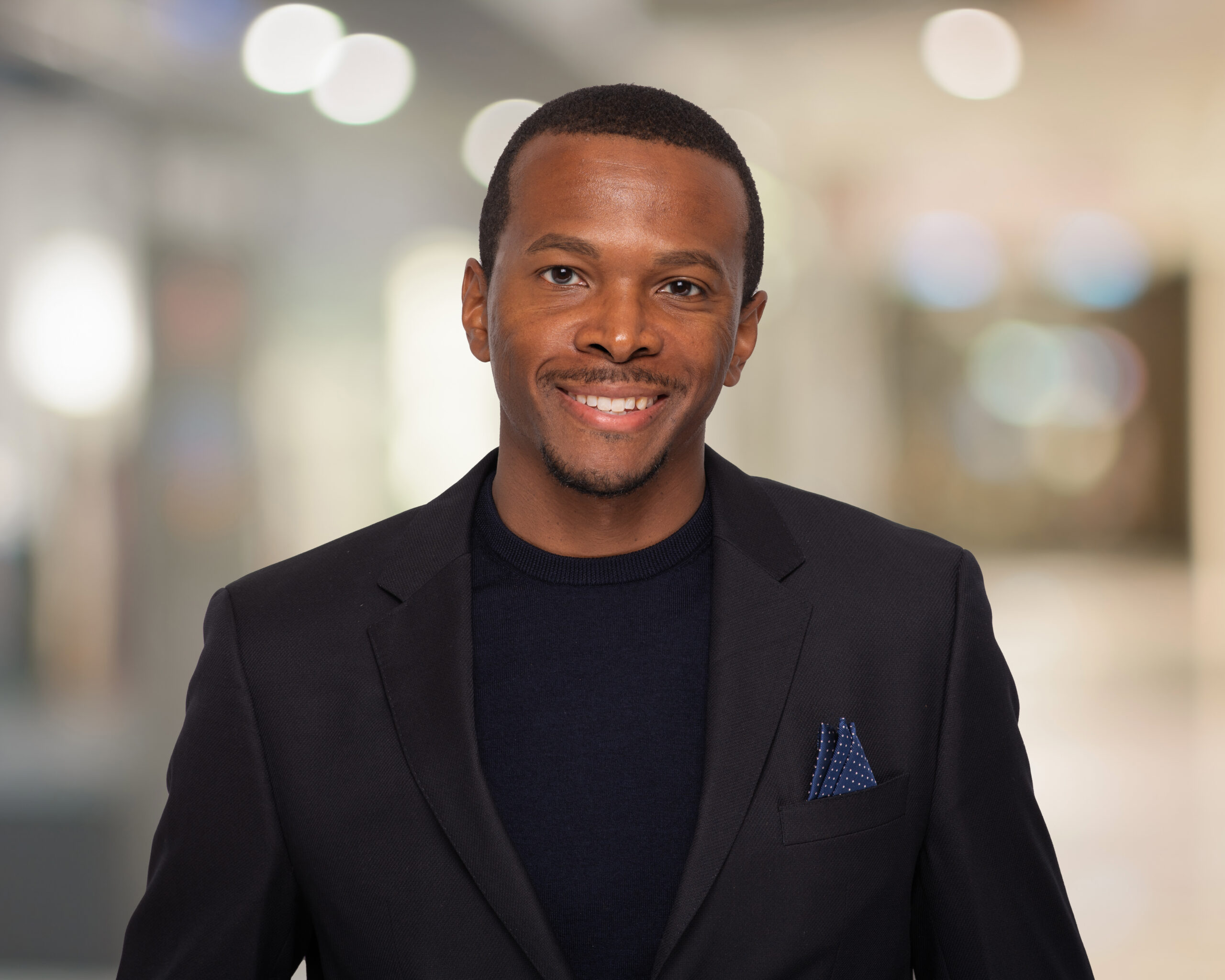 Smiling man in suit, blurred background.