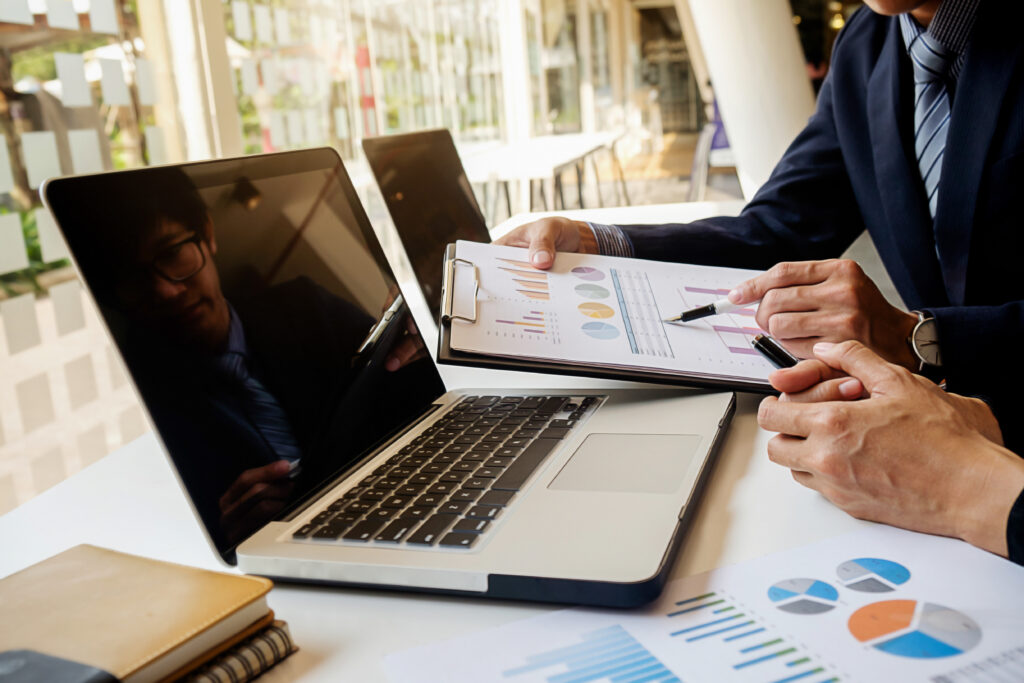 Business meeting analyzing financial graphs on laptop.