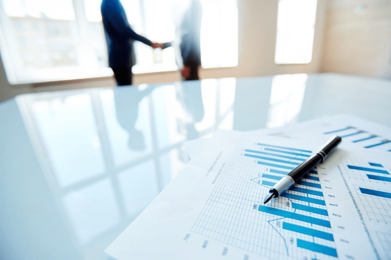 Business meeting with financial charts and handshake.