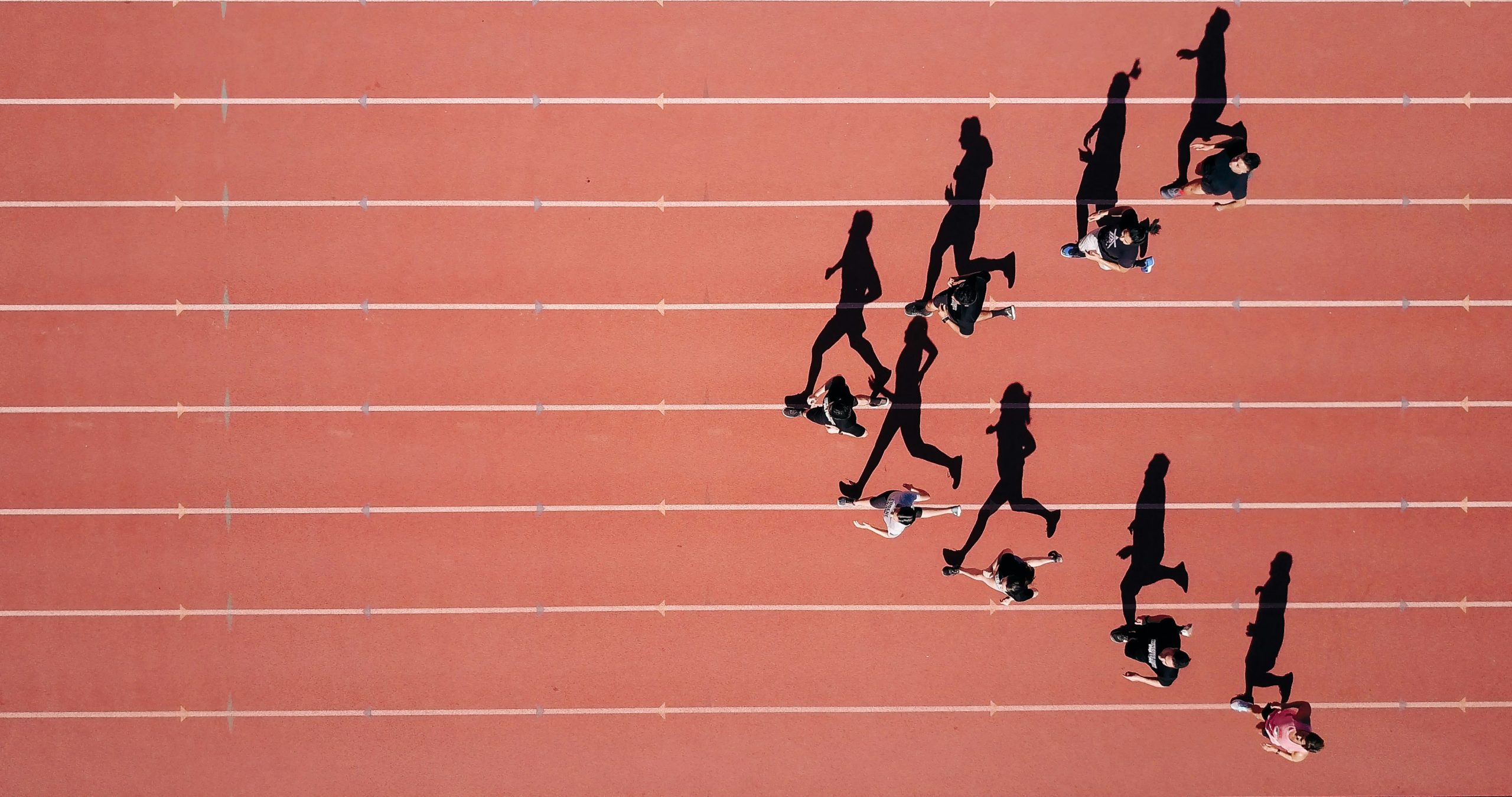 Lifeguards running on track with long shadows.