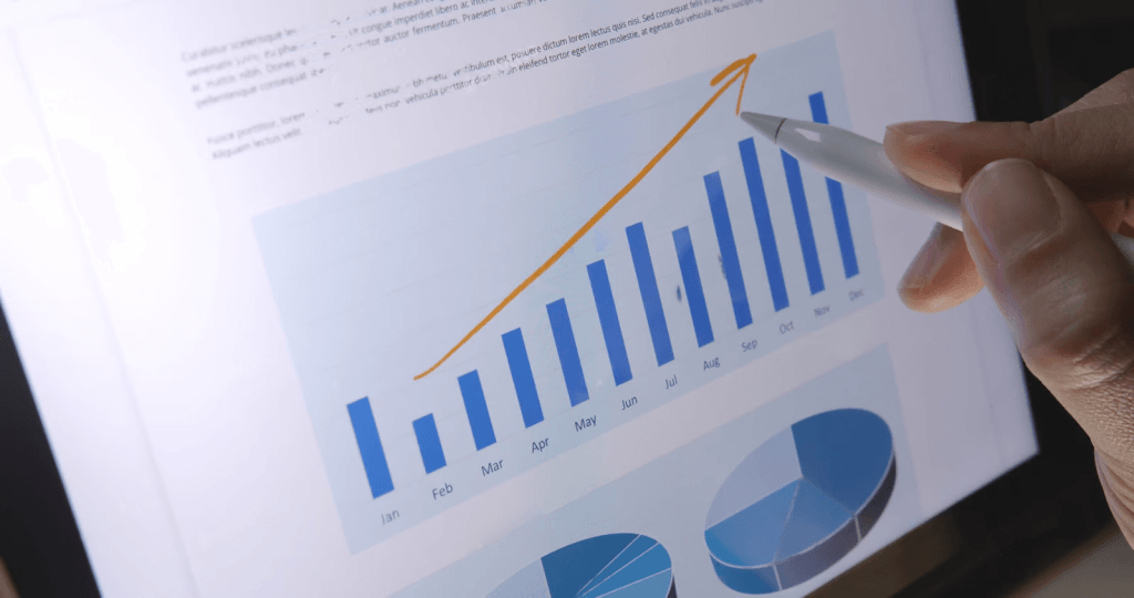 Person analyzing rising bar graph on tablet screen.